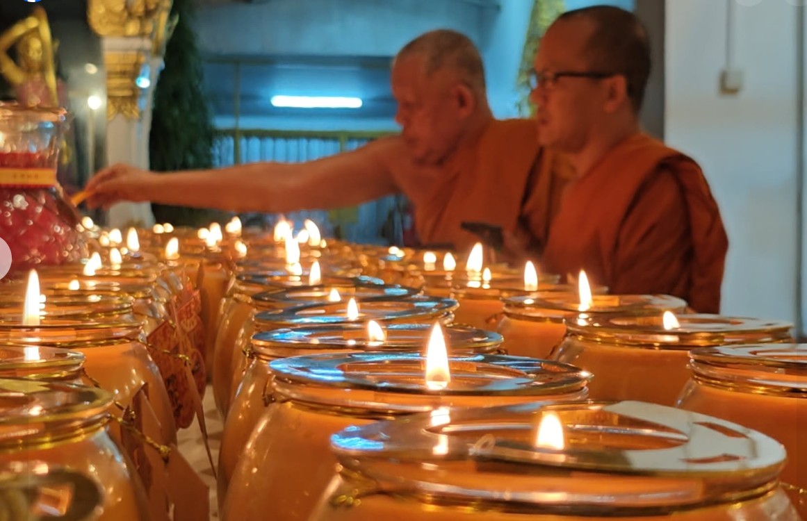Monks lighting rows of candles at the temple
